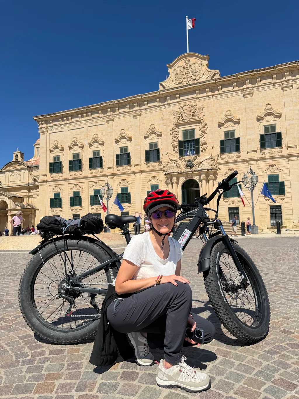 Rider with her e-bike in front of the Auberge de Castille in Valletta