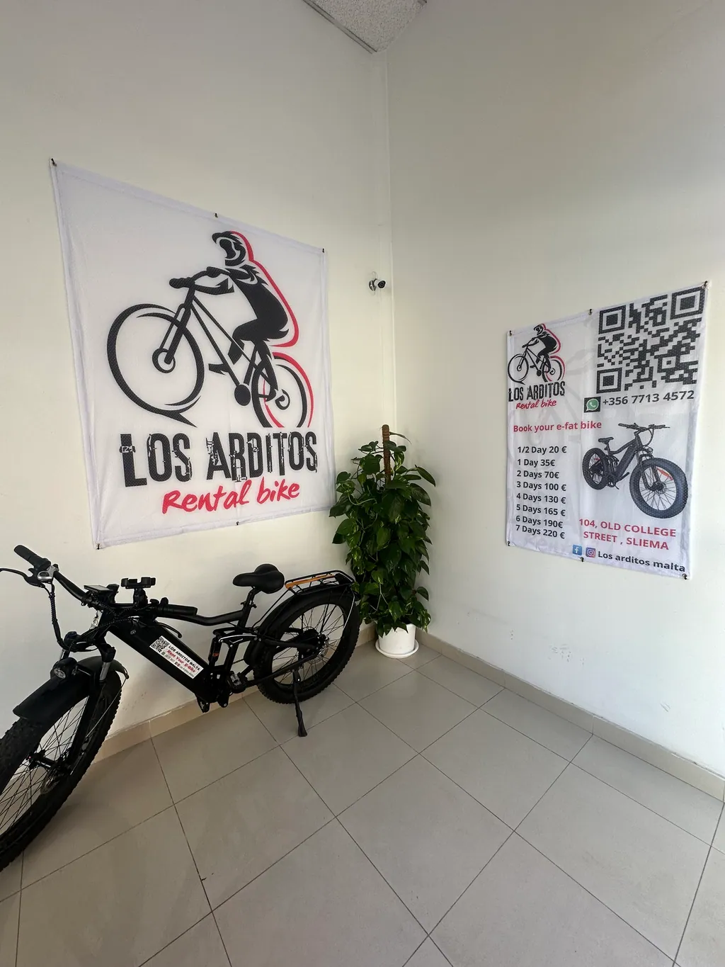 Inside the Los Arditos rental shop in Sliema with an e-bike and the shop sign
