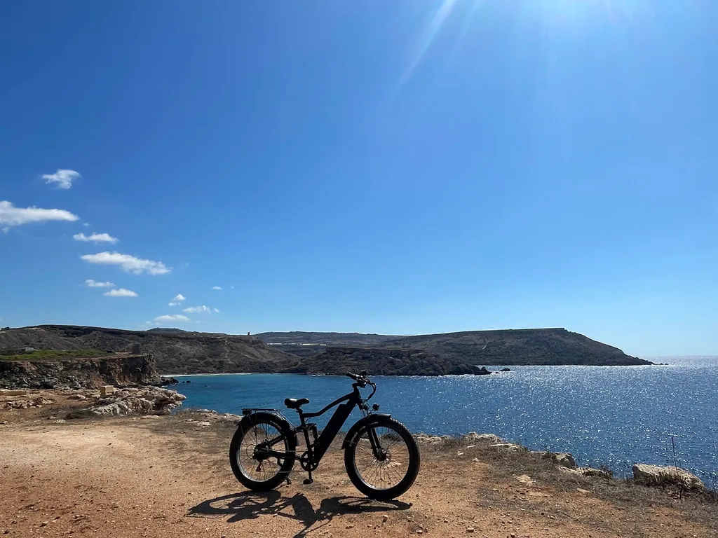 E-bike above a bay on the north coast of Malta with the headland beyond