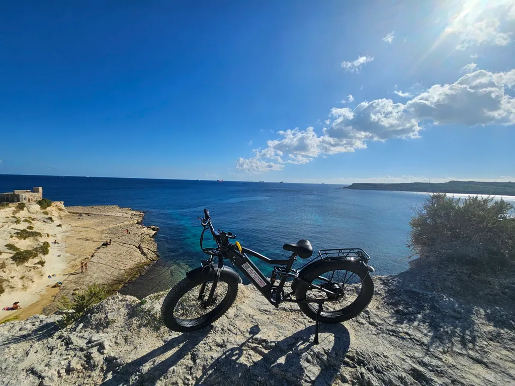 Los Arditos e-bike on the cliffs above a turquoise bay on Malta's south-east coast